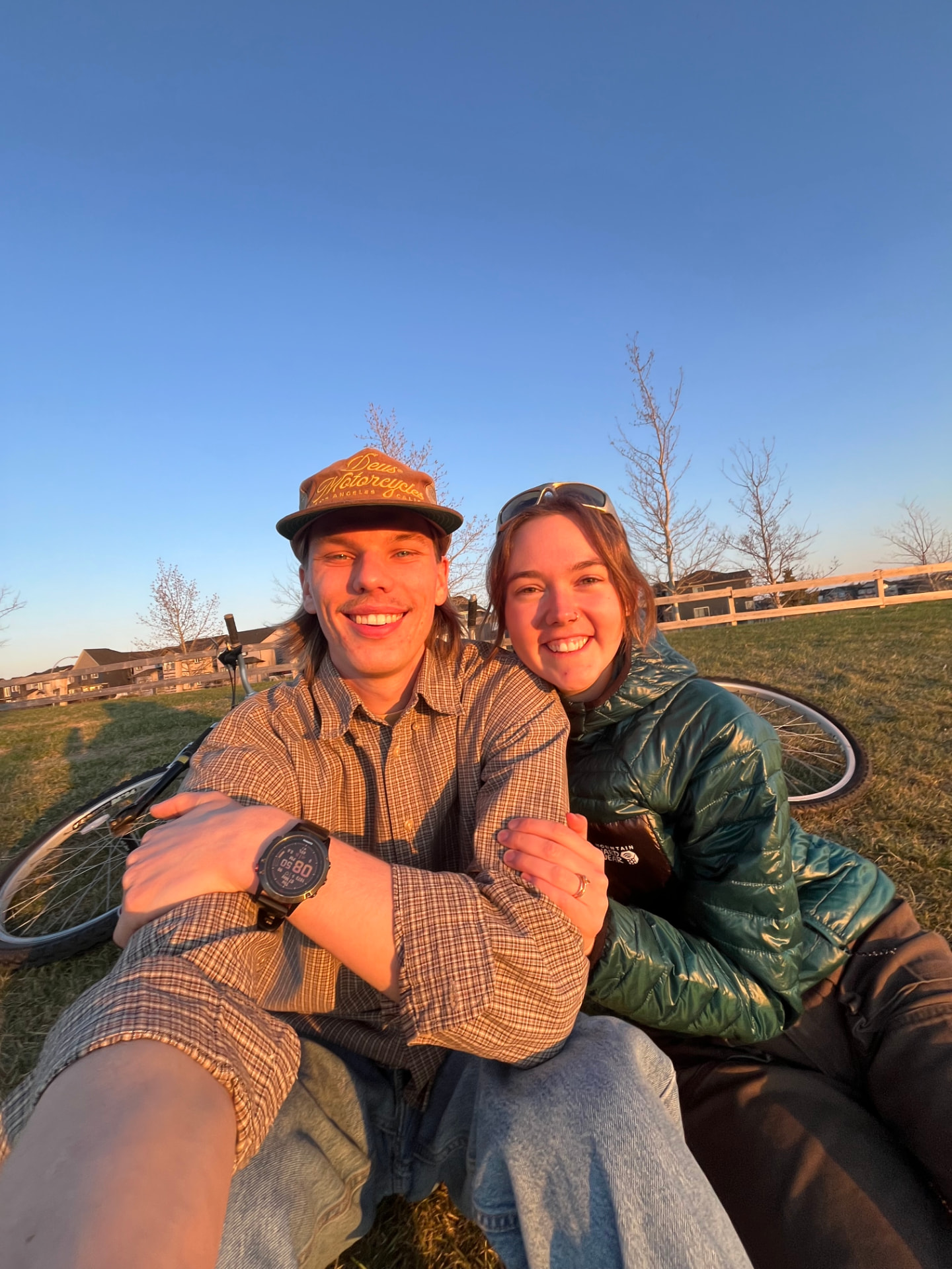 Owen and his wife Alyson sitting in a field at sunset with bikes