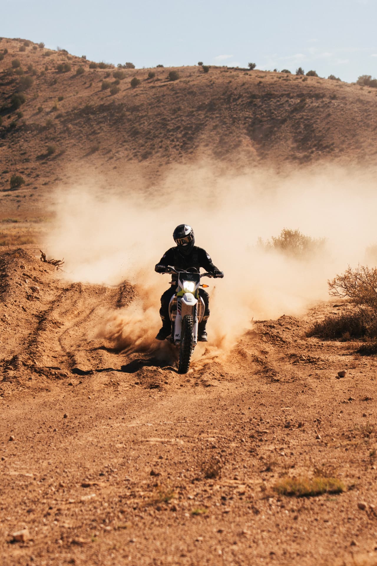 Owen riding a dirt bike through a dusty desert trail