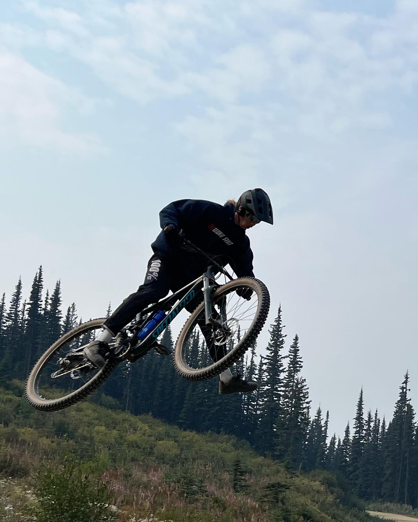 Owen catching air on a mountain bike in the forest