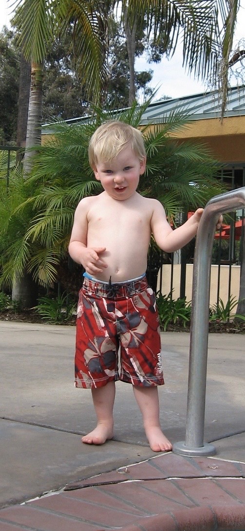 Owen as a toddler in swim trunks by a pool