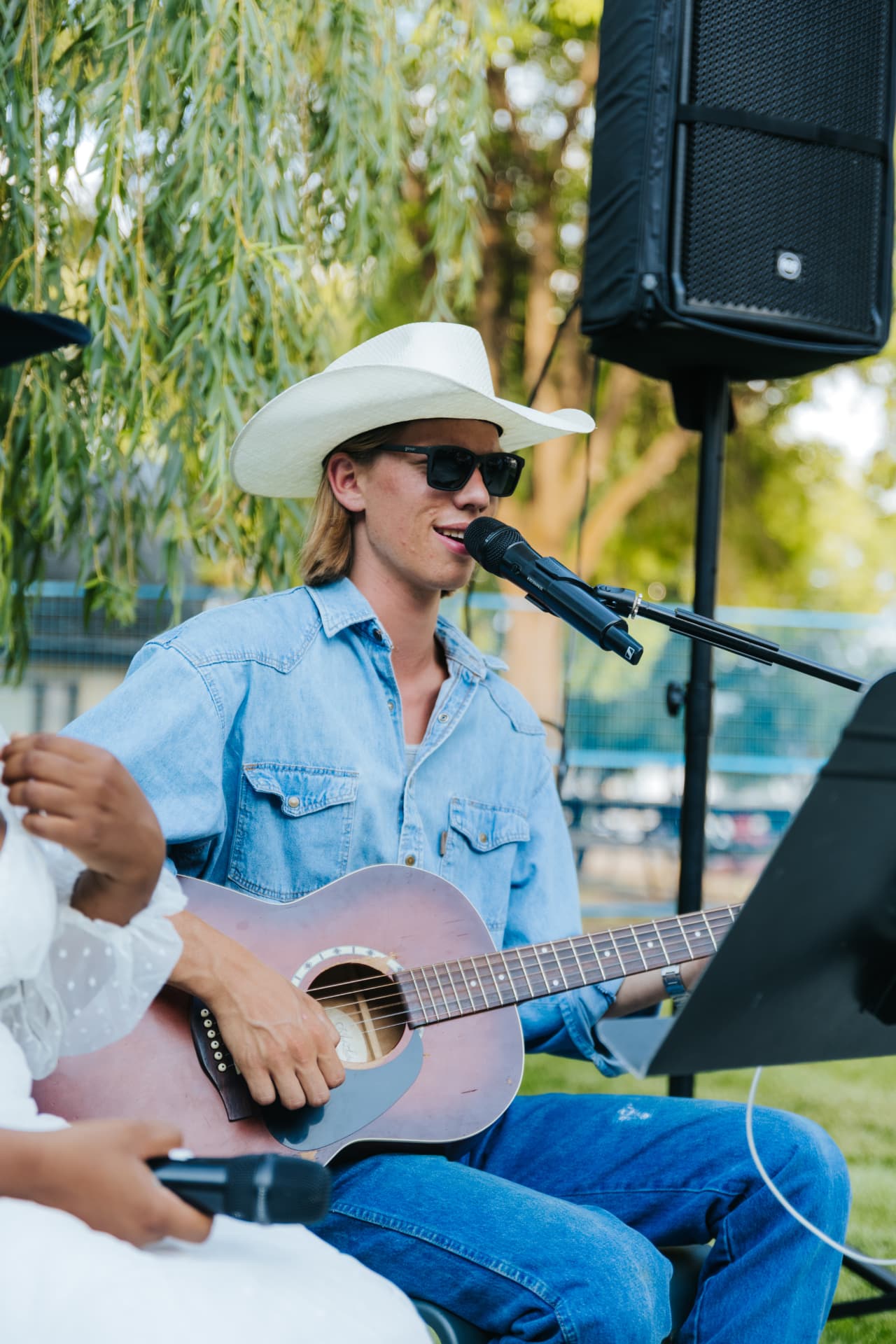 Owen playing acoustic guitar and singing outdoors in a cowboy hat